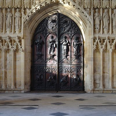 The dark wooden west door at Beverley Minster is carved with many fine details.